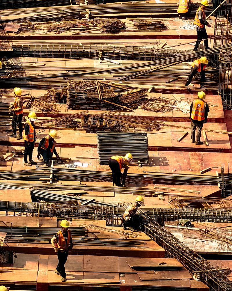 Trabalhadores de capacete e colete refletivo em um canteiro de obras.